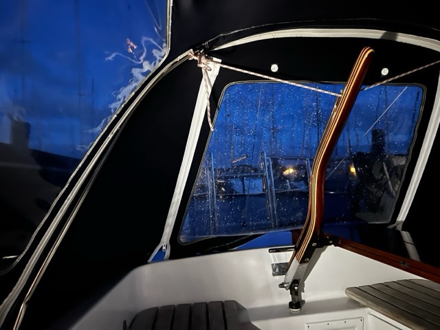 Blick durchs Sprayhood-Fenster bei Nacht im Hafen
