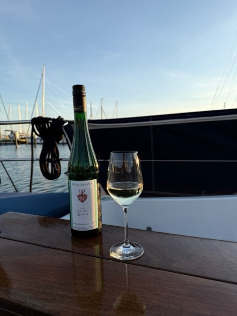 Weinglas und Flasche auf dem Niedergangsbrett im Abendlicht