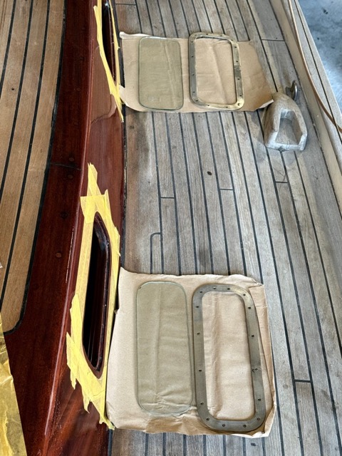 Scheiben und Rahmen liegen ausgerichtet auf Packpapier vor den Fenstern auf dem Deck