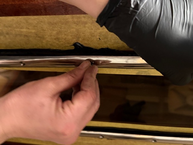 Eine Schraube wird von Hand in den Edelstahlrahmen gesetzt