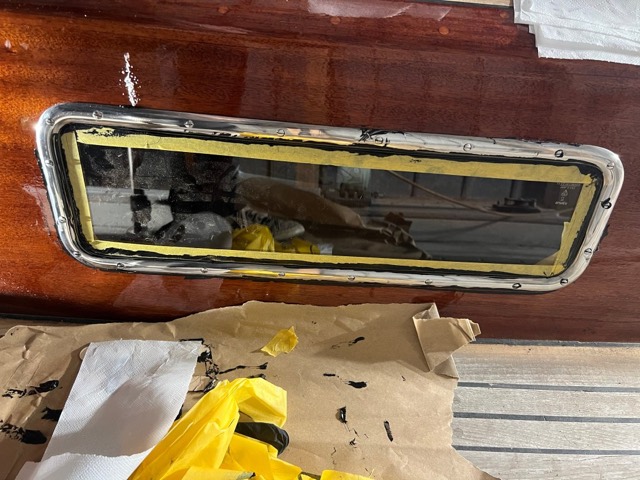 Fertig eingeklebtes Fenster, noch mit Klebeband, davor ein Haufen verschmierter Tücher