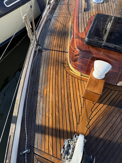 Frisch gewässertes Teakdeck im Abendlicht, mit dunklen Fugen und glänzendem Lack am Aufbau