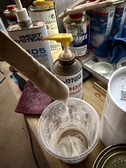 Das mit Filler angedickte Epoxy tropft zähflüssig vom Rührholz in den Becher