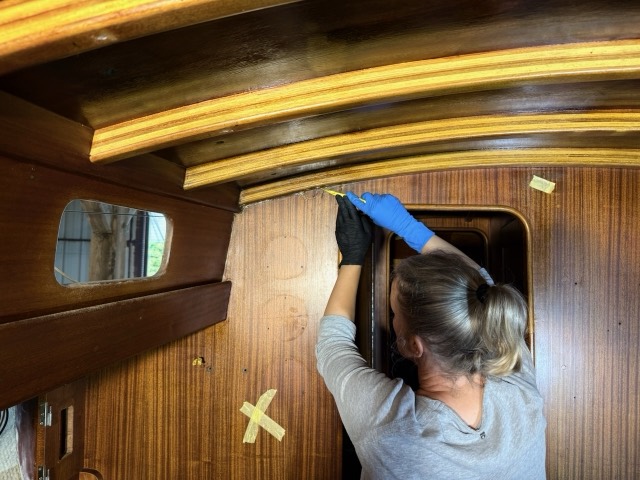 Judith kratzt mit dem Schaber die Fuge unter der Deckenleiste frei